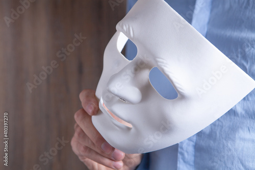 Businessman holding white mask in his hand photo