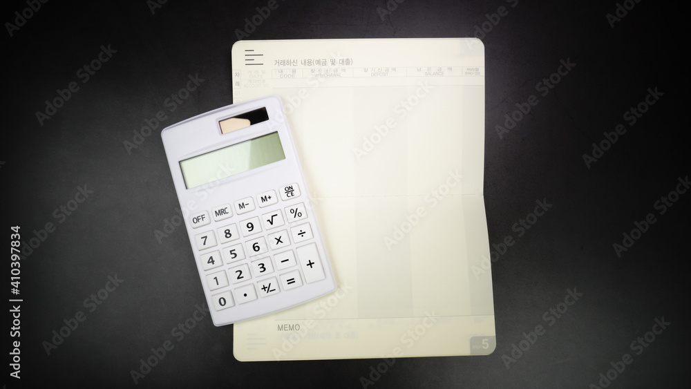 Saving Account Bankbook and Calculator on Black Marble Background. Close up. Translation: Transaction details (deposit and loan), Order Saving Account Bankbook and Calculator on Black Marble Background. Close up. Translation: Transaction details (deposit and loan), Order