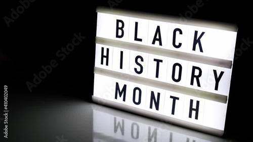 Lightbox with text BLACK HISTORY MONTH on dark black background with mirror reflection. Message historical event. 4k Video. Zoom in photo