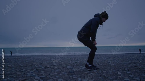 Young tall person is doing warm up. Training on open air at nasty weather photo