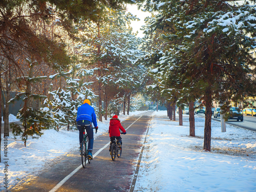 Father and son ride bicycles on the bike path in winter. Cycling as a sustainable and healthy form of urban transport