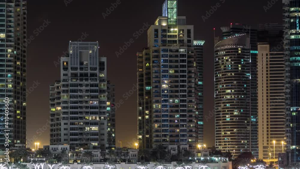 Promenade and canal in Dubai Marina timelapse at night, UAE. Aerial view from bridge with palms, floating boats and illuminated towers. Harbor with yachts Promenade and canal in Dubai Marina timelapse at night, UAE. Aerial view from bridge with palms, floating boats and illuminated towers. Harbor with yachts