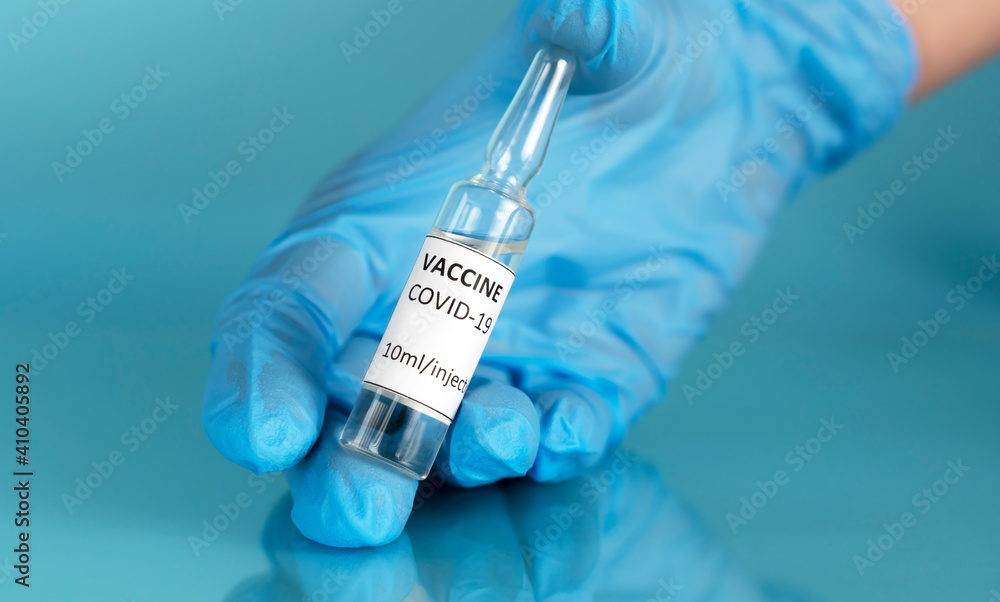 Coronavirus vaccine. The doctor's gloved hand holds vaccine ampoule in the lab for Covid-19 vaccination. Stop Covid. Back to normal life. Take off face mask. Horizontal orientation. Coronavirus vaccine. The doctor's gloved hand holds vaccine ampoule in the lab for Covid-19 vaccination. Stop Covid. Back to normal life. Take off face mask. Horizontal orientation.