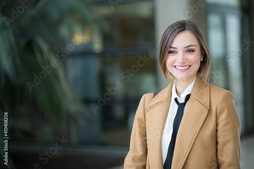 bella manager con camicia bianca e cappotto in contesto urbano , guarda lontano sorridente photo