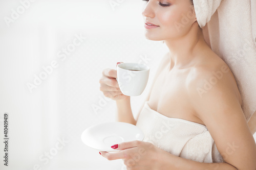 Fototapeta Naklejka Na Ścianę i Meble -  Woman drinking morning coffee. Attractive young female in towel after bathing or taking shower.