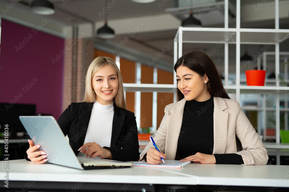 two beautiful young women in the office with a laptop two beautiful young women in the office with a laptop