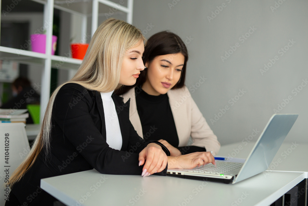 two beautiful young women in the office with a laptop two beautiful young women in the office with a laptop