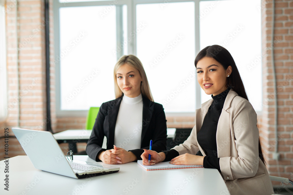 two beautiful young women in the office with a laptop two beautiful young women in the office with a laptop