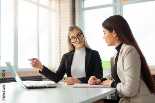 two beautiful young women in the office with a laptop 