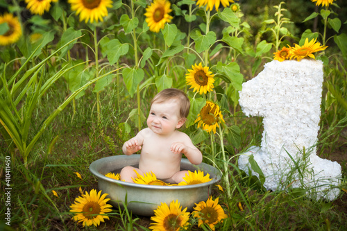Cute baby girl in a basin on a sunflower field