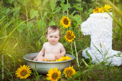 Cute baby girl in a basin on a sunflower field