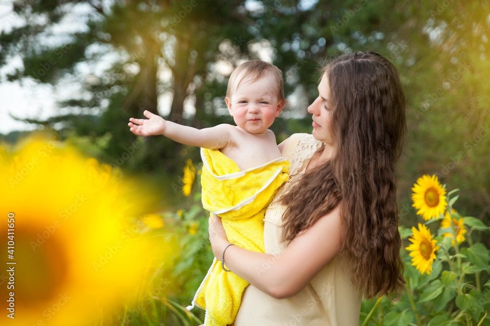 Cute baby girl with her mother in a sunflower field Cute baby girl with her mother in a sunflower field