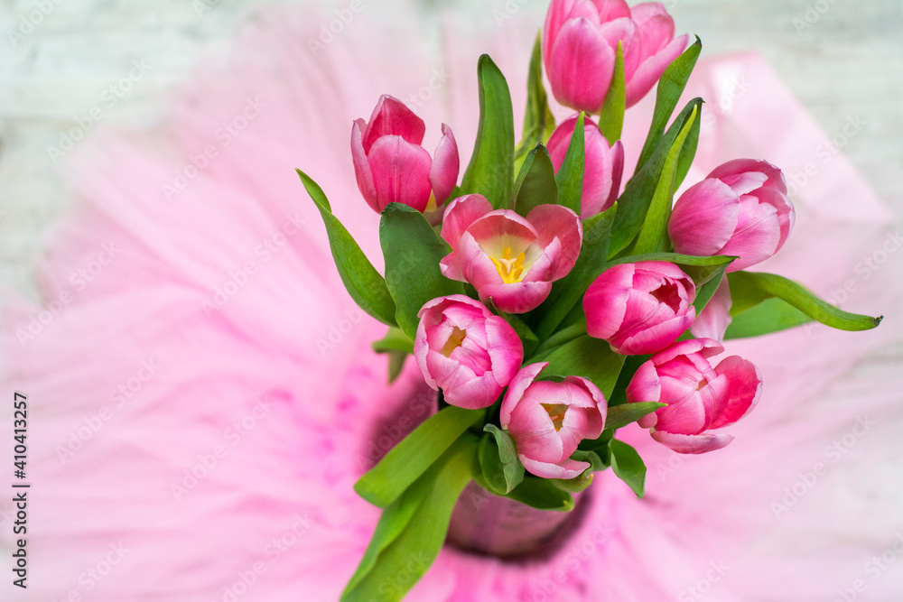 One beautiful bouquet of pink tulips on the pink background. Spring flowers with green leaves