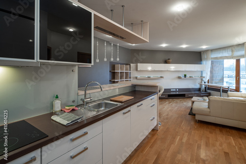 Contemporary interior of kitchen in luxury studio apartment. Modern kitchen set with dark wooden counter and sink.