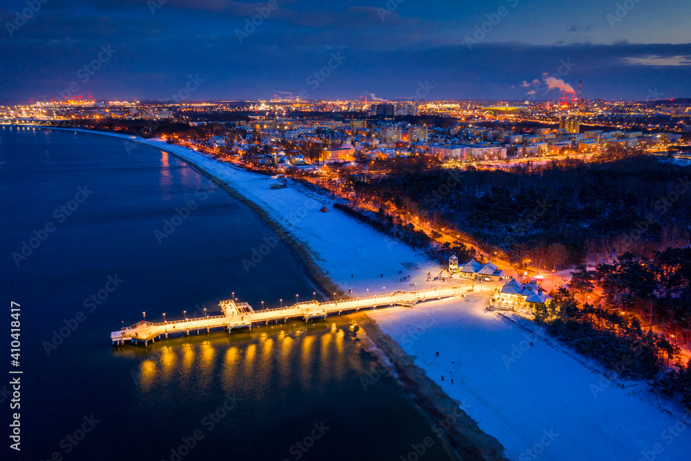 Illuminated pier in Brzezno on the winter beach at dusk, Gdansk.  Poland.