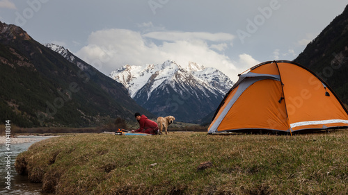 girl traveler in a camp at the foot of the mountain with her dog