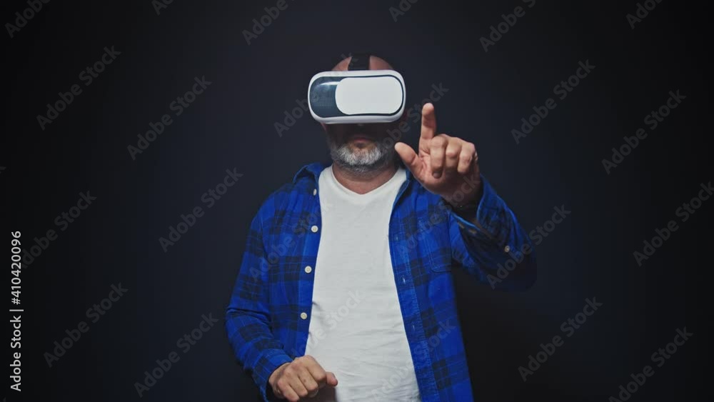 Mature man using VR headset for virtual reality in studio Mature man using VR headset for virtual reality in studio