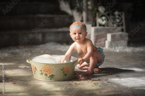 baby plays in the basin in the yard of the house. Retro