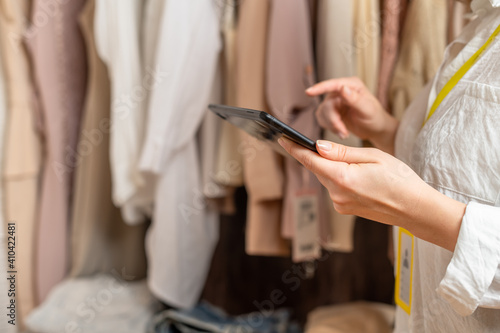 Female entrepreneur holding tablet while doing inventory in her trendy clothing shop