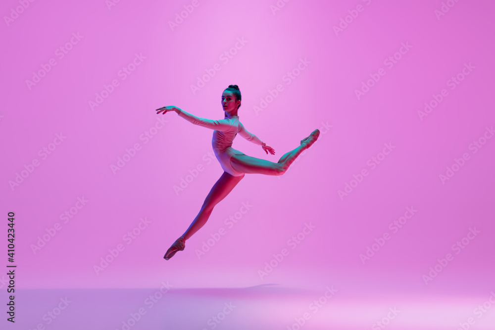 Inspiration. Young and graceful ballet dancer on pink studio background in neon light. Art, motion, action, flexibility, inspiration concept. Flexible caucasian ballet dancer, moves in glow.