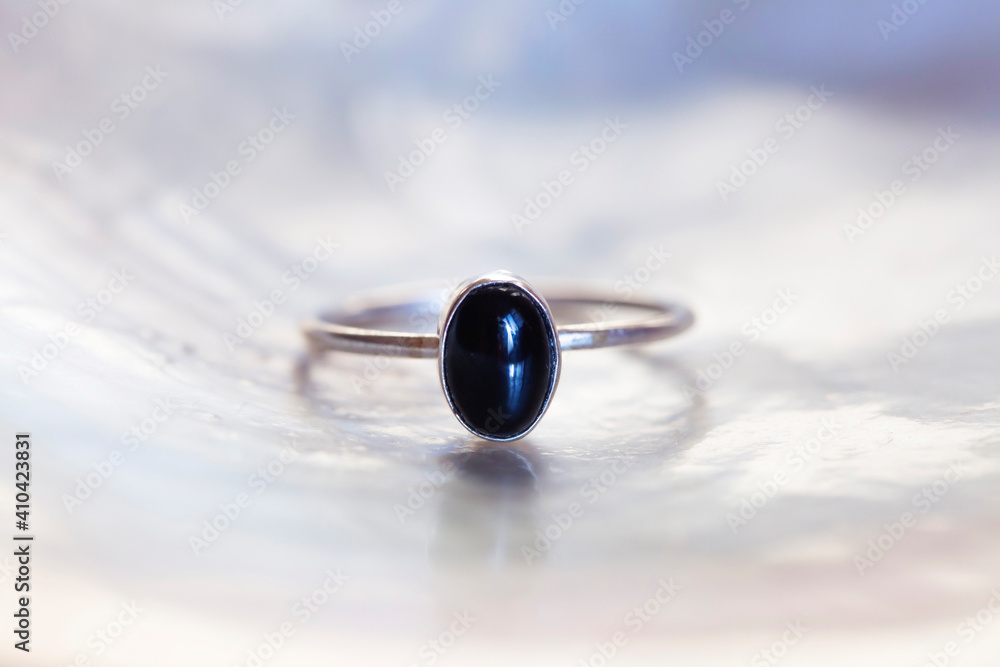 Fototapeta premium Antique silver ring with black onyx mineral stone on white shell background