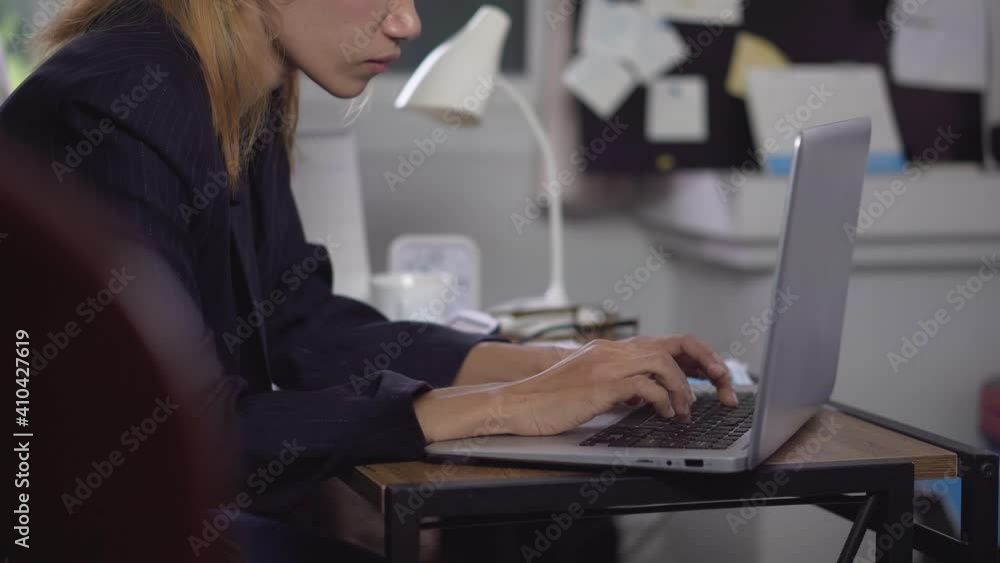 Asian woman typing on laptop at home office. Serious financial female wear casual and glasses. Technology concept. Asian woman typing on laptop at home office. Serious financial female wear casual and glasses. Technology concept.