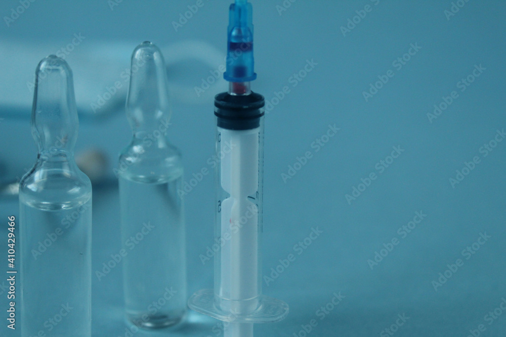 vaccination syringe and vials with medicine close-up on a blue background with a copyspace vaccination syringe and vials with medicine close-up on a blue background with a copyspace