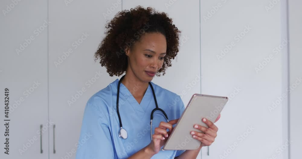 Portrait of mixed race female doctor using tablet and smiling Portrait of mixed race female doctor using tablet and smiling