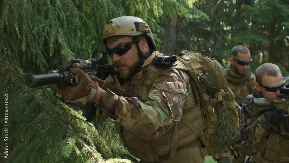 Medium closeup of squad of special forces with rifles on secret operation in jungle, investigating territory Medium closeup of squad of special forces with rifles on secret operation in jungle, investigating territory