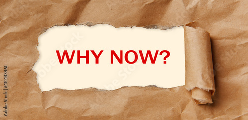 Text - WHY NOW - appearing behind torn brown paper