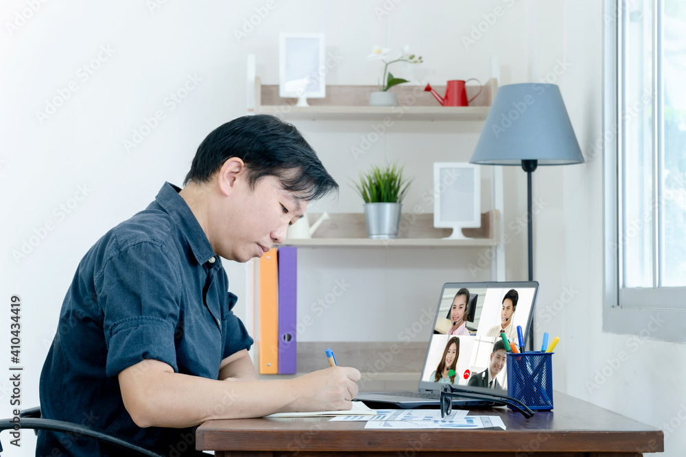 Online training. Young guy learns online by video conference. On the screen, the teacher tells the information Online training. Young guy learns online by video conference. On the screen, the teacher tells the information