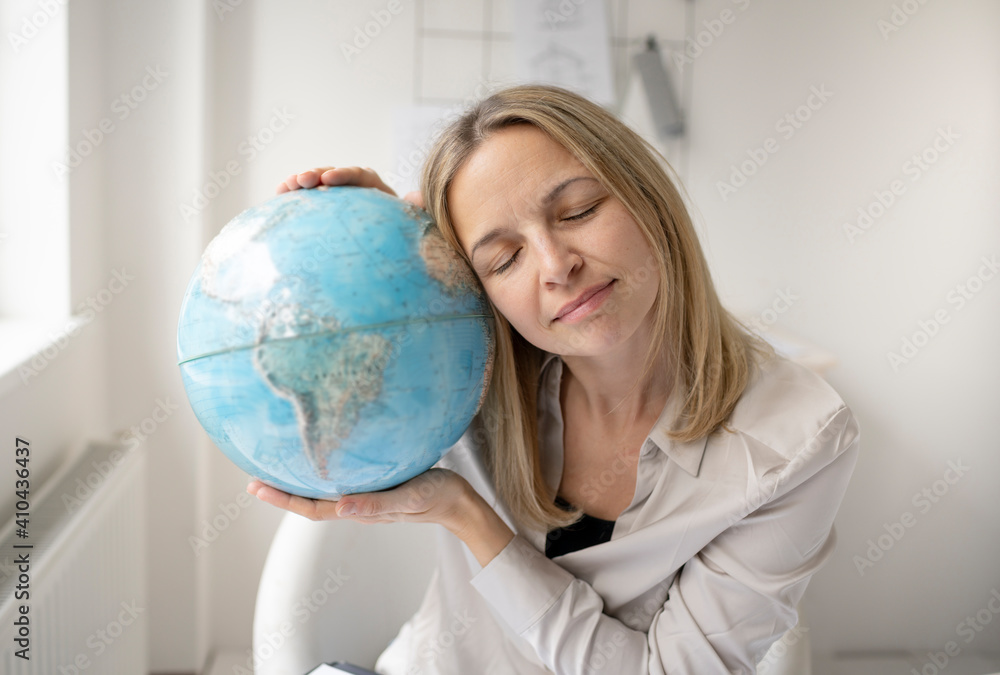 young, beautiful female architect is sitting in her office and is holding a globe and is dreaming of travelling around the world after corona or covid 19 young, beautiful female architect is sitting in her office and is holding a globe and is dreaming of travelling around the world after corona or covid 19