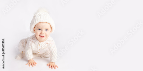 baby crawls in a warm suit and hat on a white isolated background, space for text, banner