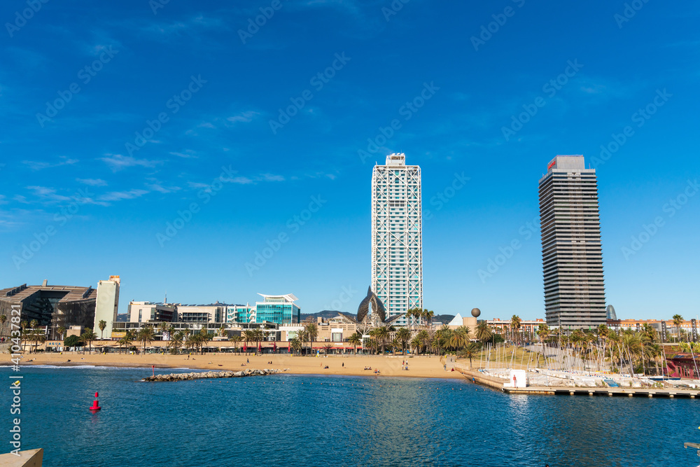 BARCELONA, SPAIN, FEBRUARY 3, 2021: Famous towers of the port of Barcelona, the Mapfre Tower and the Hotel Arts. Sunny winter day. During the covid-19 pandemic. Barcelona Skyline.