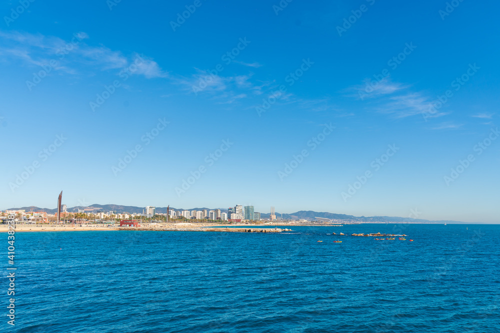 BARCELONA, SPAIN, FEBRUARY 3, 2021: Barcelona coast a sunny winter day. During the covid-19 pandemic. View from inside the water. In the background we can see the new modernist buildings on the coast.