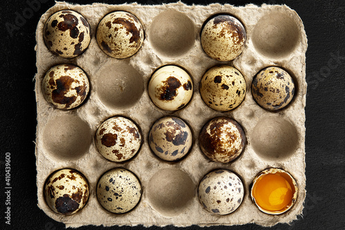 Quail eggs in the cardboard packing on the grey scratched table.