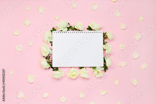 Floral frame of white roses and petals around notebook © ukrolenochka