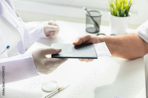 Doctor in gloves gives to patient passport with Coronavirus Vaccination Card, Covid-19 Vaccination Card for travel abroad. Selective focus.