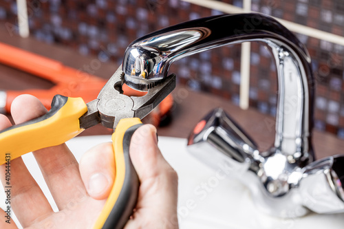 plumbing faucet repair concept. plumber using wrench tool and pliers to adjusting tap leak at bathroom. diy plumber conceptual