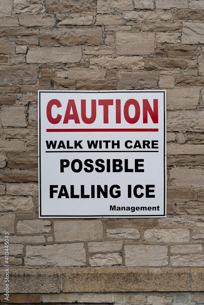Caution possible Falling ice red and white sign on stone wall Caution possible Falling ice red and white sign on stone wall