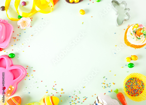 Easter set frame with eggs, cookie cutter, candies, cupcake. Top view. Copy space.