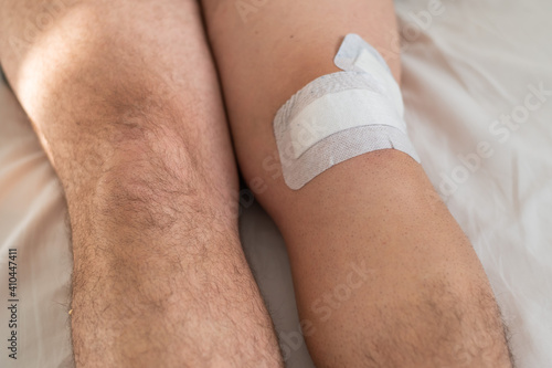 Close-up of male legs with knee taped with tape after laparoscopic minisk surgery photo