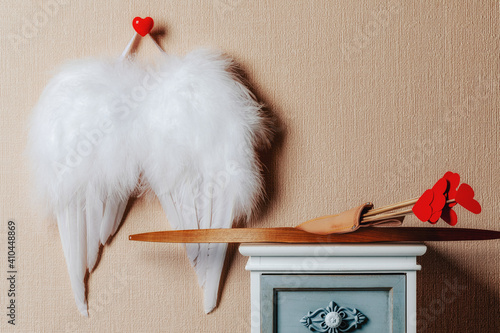 Angel wings hanging on the wall . Cupid weapons set bow and arrows on the nightstand. Valentines Day concept. photo