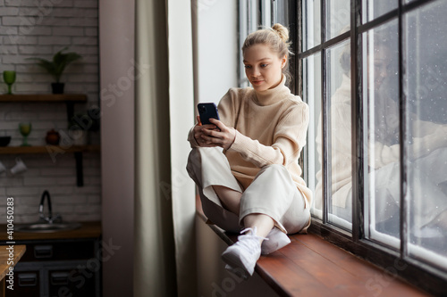 Happy teen girl checking social media holding smartphone at home. Using mobile phone shopping online, ordering delivery