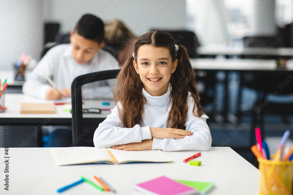 Portrait of small girl sitting at desk in classroom Portrait of small girl sitting at desk in classroom
