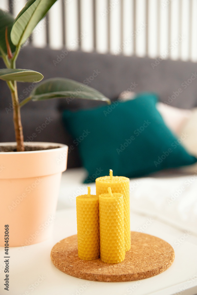 Scandinavian interior, yellow honey scented beeswax candle on bedroom cabinet