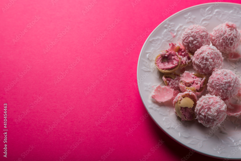 delicious coconut candies with pink cream lie on a white plate on a bright pink background. Photos for printing, cooking courses. High quality photo delicious coconut candies with pink cream lie on a white plate on a bright pink background. Photos for printing, cooking courses. High quality photo