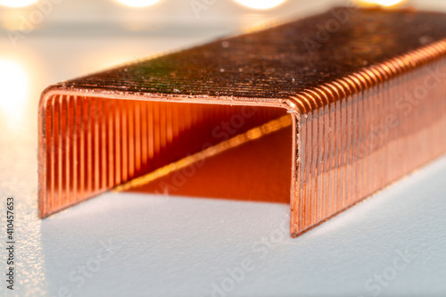 Coppered staples photographed close-up in white tones. Group of copper staples placed diagonally as if it were a tunnel with the light coming from behind. photo