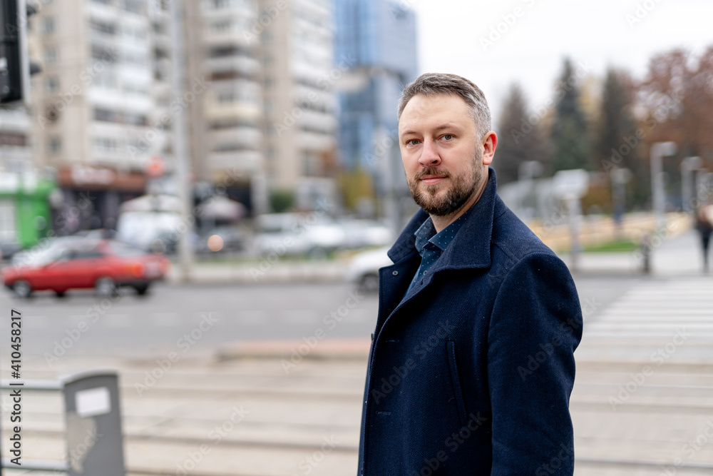 Portrait of a handsome young businessman dressed in formal clothes. Male in coat is looking to the camera with city view background. Portrait of a handsome young businessman dressed in formal clothes. Male in coat is looking to the camera with city view background.