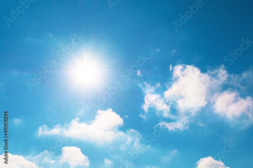 Bright blue sky and sun flare in spring sky with clouds vapor.